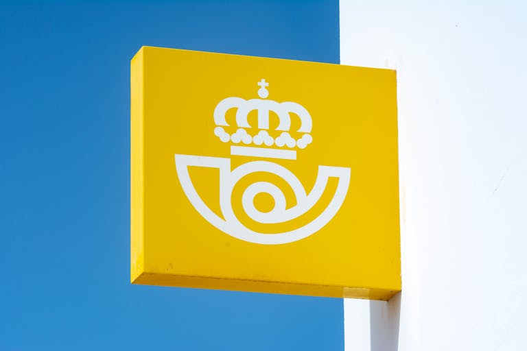Sign for Spanish postal service against blue sky, capturing iconic symbol.