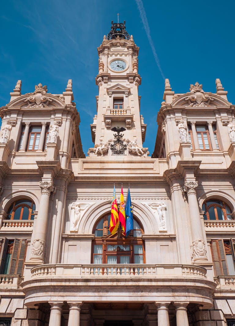Stunning facade of Valencia City Hall with flags under a clear blue sky.